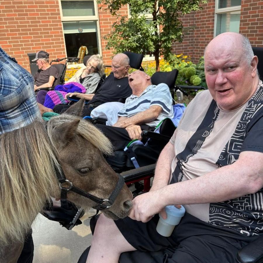 A resident holds the miniature pony while other residents look on