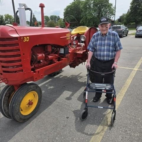 A resident with a walker beside a red Massey Harris 30